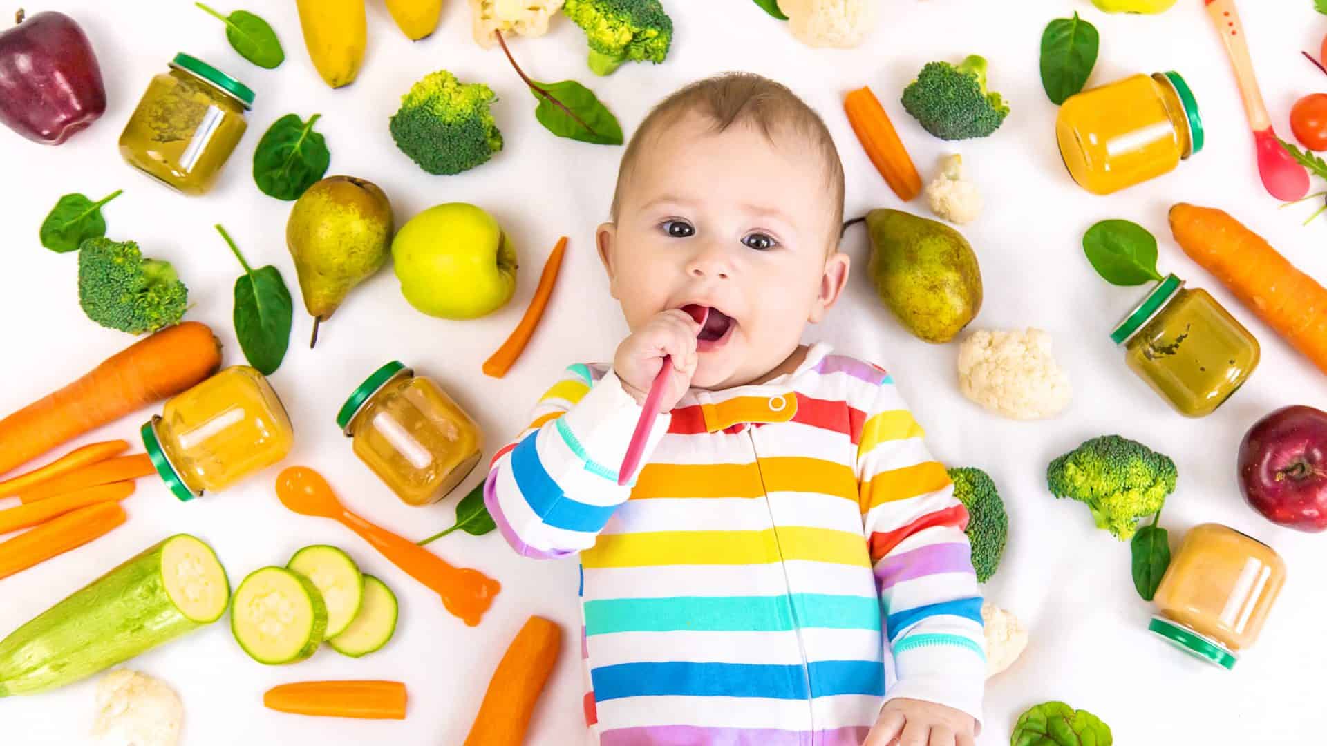 Bebê cercado de frutas, verduras, legumes e vegetais