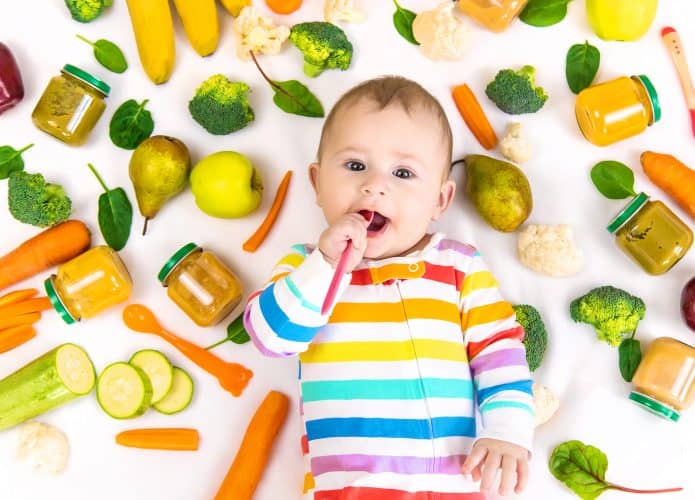 Bebê cercado de frutas, verduras, legumes e vegetais