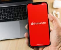 Mão masculina segurando um smartphone com o aplicativo do banco Santander na tela.
