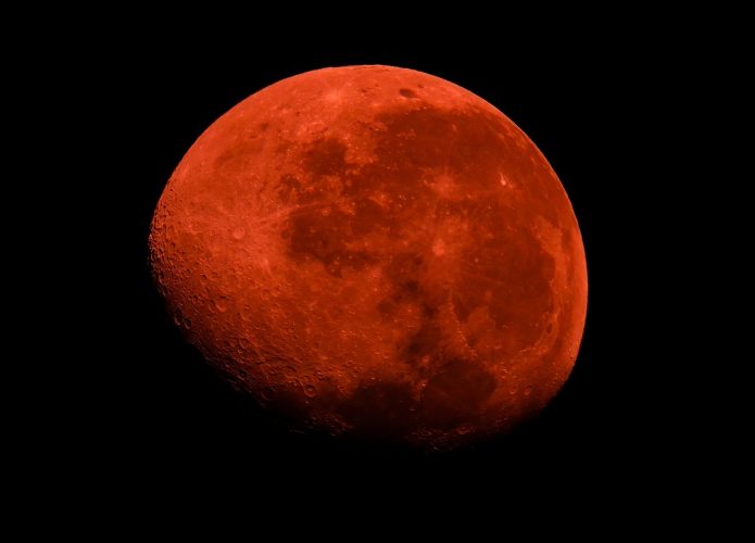 Uma imagem impressionante de um eclipse da Super Lua de Sangue no céu noturno, com a lua cheia brilhando em um tom vermelho-sangue