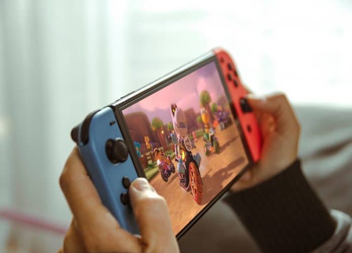 Jovem brincando com um console portátil Nintendo Switch.