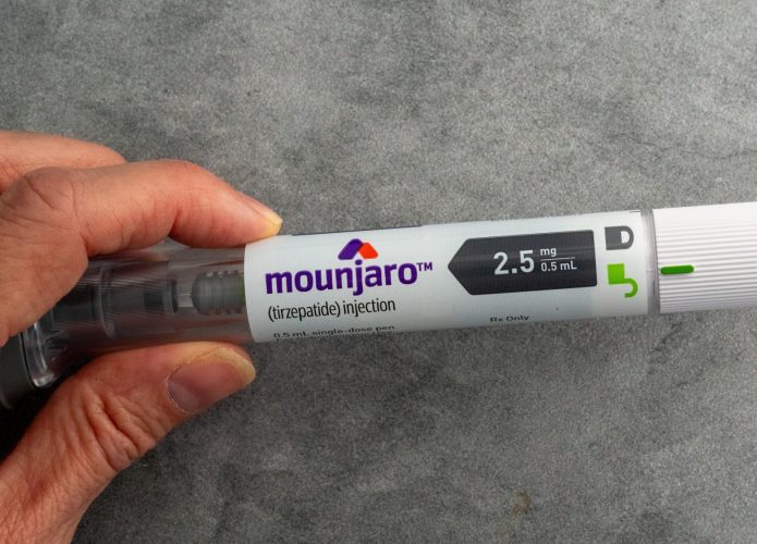 Mão segurando uma caneta injetável Mounjaro