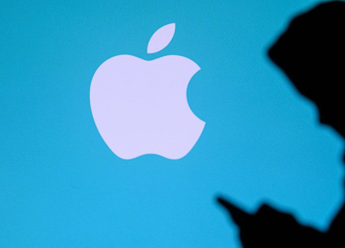 NOVA YORK, EUA, 25 DE MAIO DE 2020: A Apple, empresa multinacional americana de tecnologia, um jovem conversa em um celular. Logotipo da empresa na tela ao fundo.