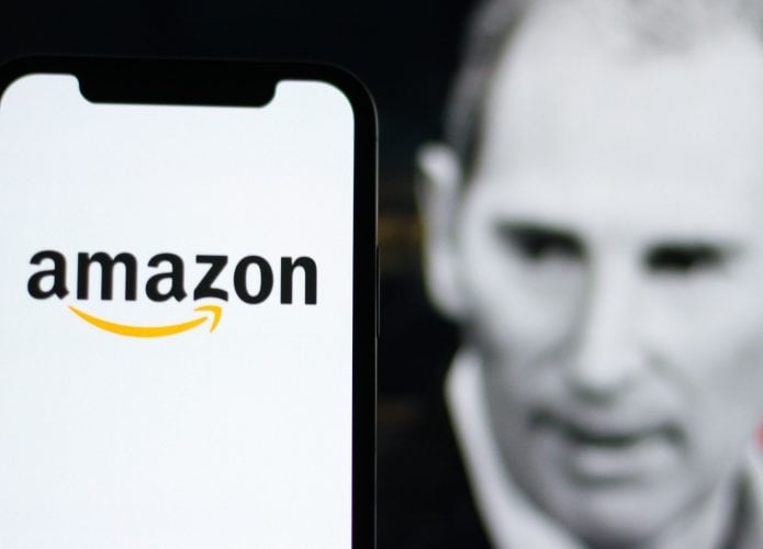Celular com logomarca da Amazon na tela colocado na frente de monitor exibindo imagem em preto e branco, com contorno vermelho, do CEO da Amazon