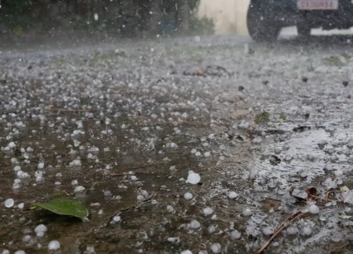Rua cheia de pedrinhas de gelo durante chuva de granizo