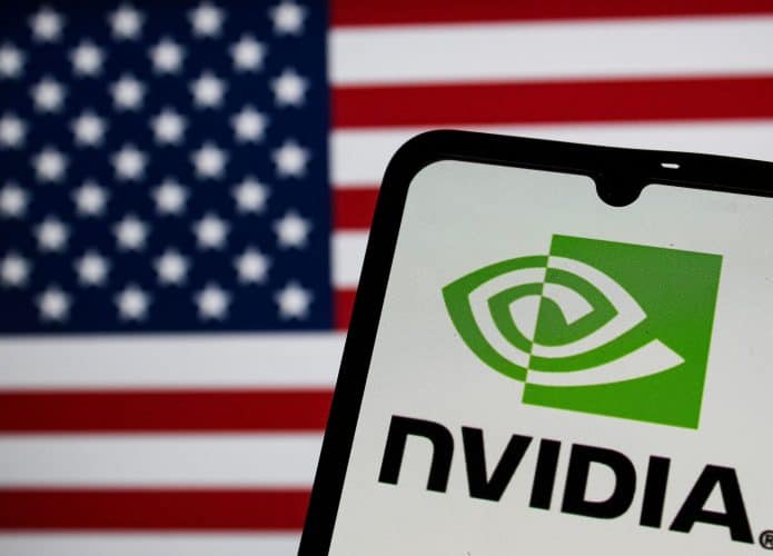 Celular exibindo logomarca da Nvidia na tela na frente de outra tela exibindo bandeira dos Estados Unidos