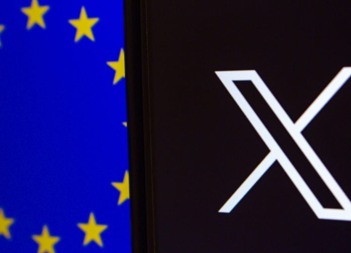 Celular exibindo logotipo do X/Twitter na tela na frente de outra tela exibindo bandeira da União Europeia