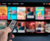 Pessoa apontando controle para TV com serviço de streaming aberto