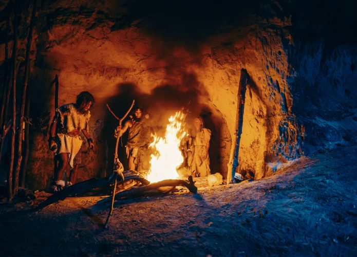 Homens das cavernas em volta de fogueira
