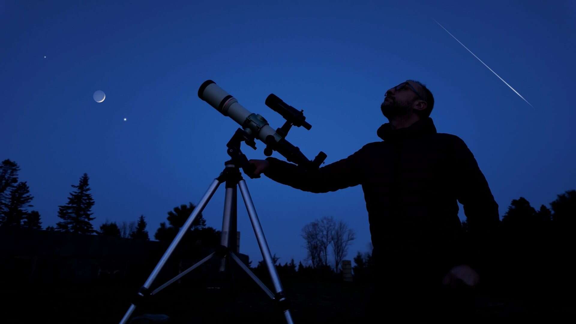 Astrônomo amador com seu telescópio olhando para o céu noturno.