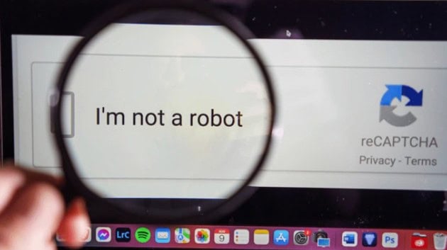 pessoa segurando uma lupa em um captcha na tela do computador