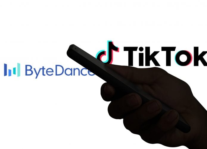 Logos de TikTok e ByteDance divididos por uma sobra de uma mão segurando um smartphone