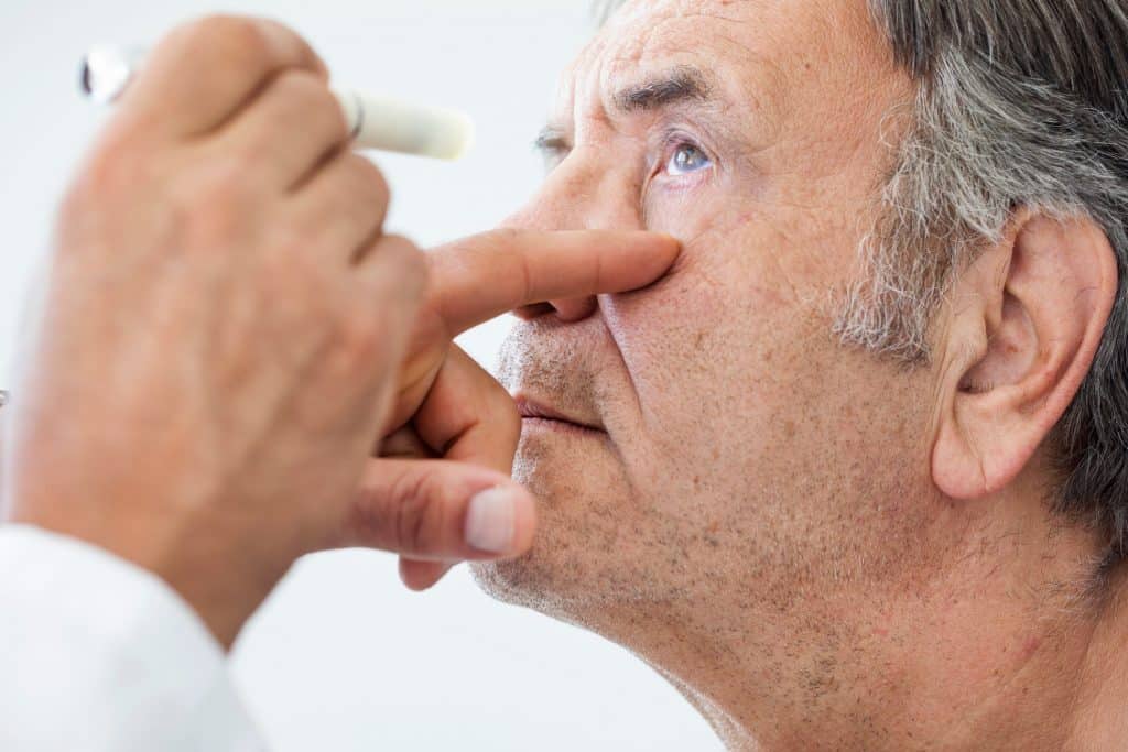 Médico examina olho de paciente homem mais velho