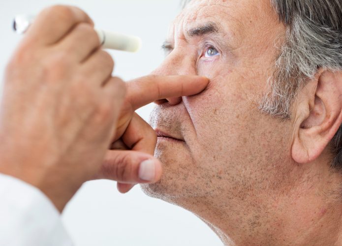 Médico examina olho de paciente homem mais velho