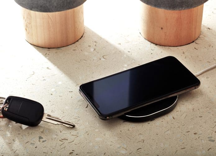 Um iPhone sendo carregado via indução ao lado de uma chave de carro