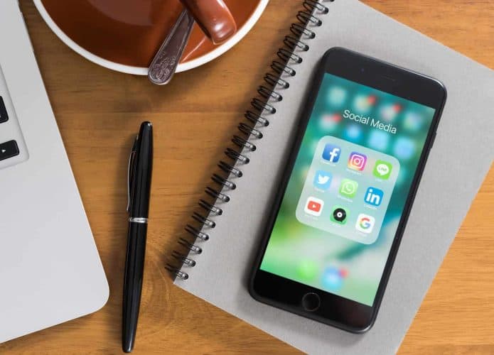 iPhone com aplicativos abertos na tela em cima de um caderno