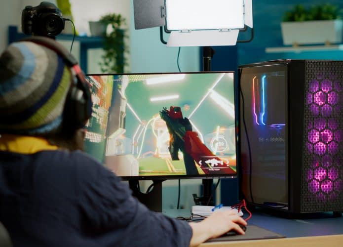 imagem mostra uma pessoa de costas para a câmera, jogando um game em um desktop/pc