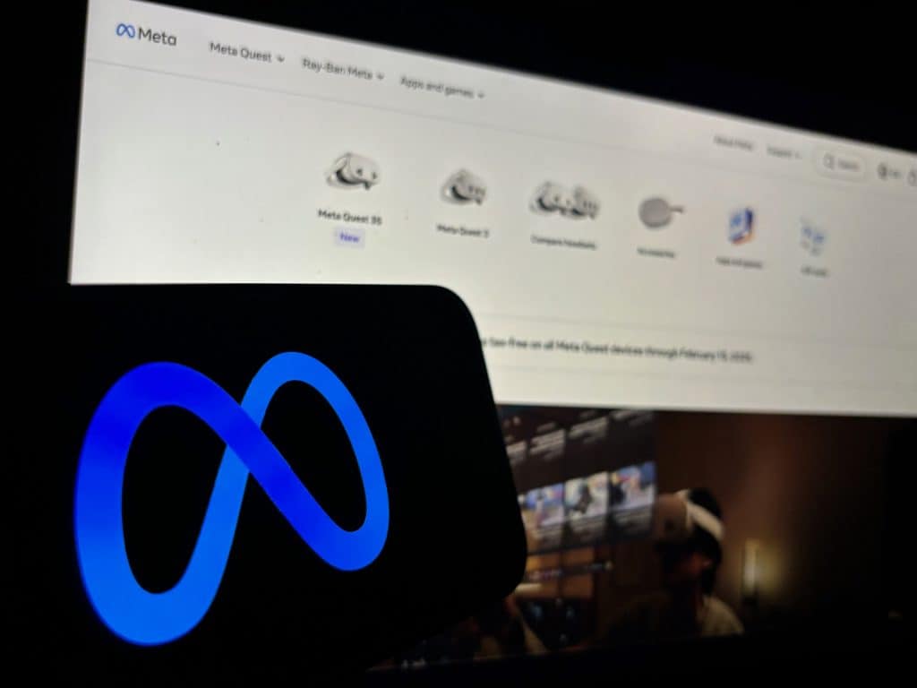 Ao fundo, página da Reality Labs desfocada; à frente, o logo da Meta em um smartphone que se encontra na horizontal
