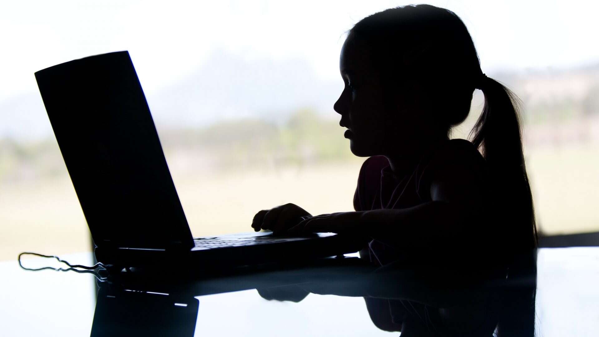 silhueta de criança usando um computador