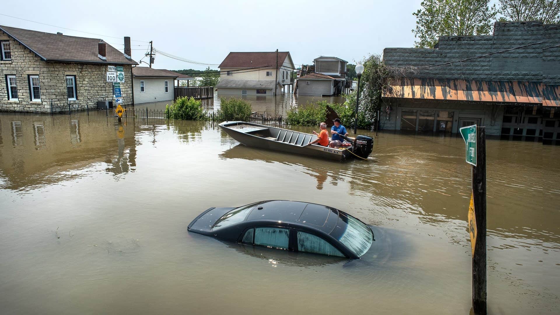 rua inundada com barco realizando resgates
