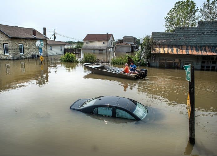 rua inundada com barco realizando resgates