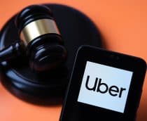 Martelo de juiz ao lado de um smartphone cuja tela exibe o logo da Uber