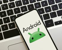 Logotipo do Android na tela do celular. Um smartphone sobre um laptop exibindo o novo logotipo do Android