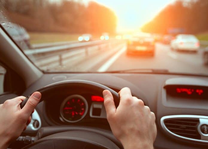 dirigindo na rodovia, close-up das mãos do motorista no volante, viagem ao pôr do sol