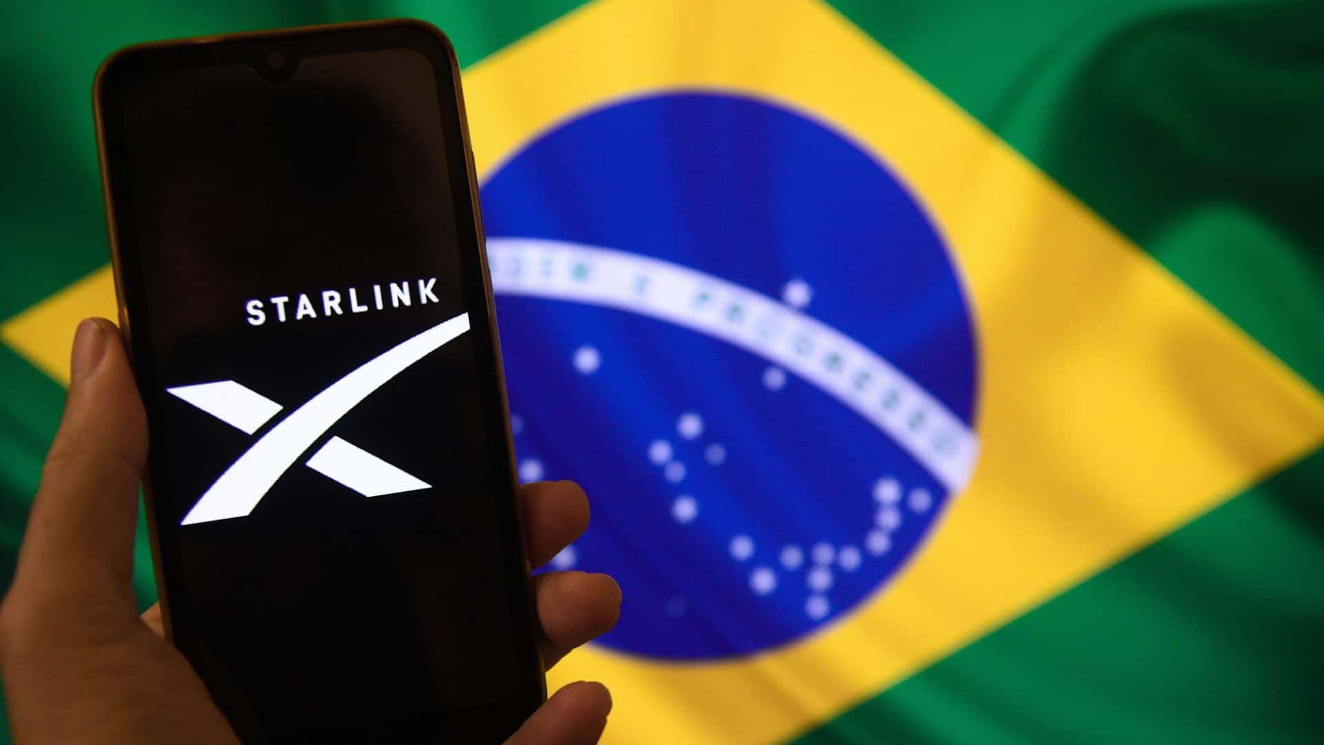logo da starlink em celular sobre a bandeira do brasil