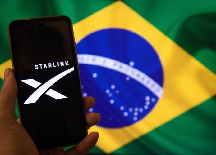 logo da starlink em celular sobre a bandeira do brasil