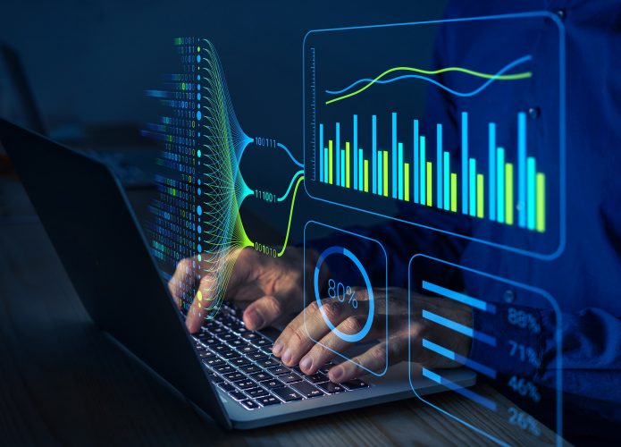 Pessoa digitando em um teclado de notebook com gráficas pairando à sua frente