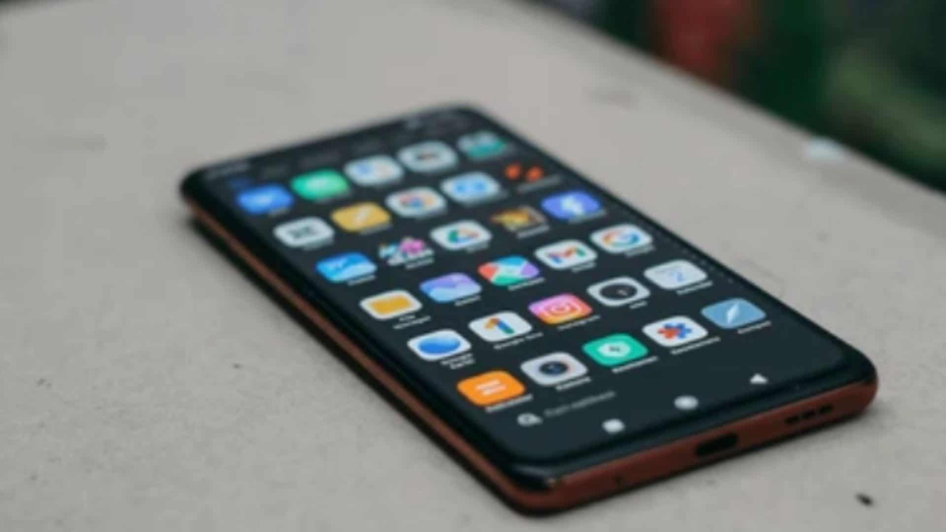 celular xiaomi mostrando tela de aplicativos em cima de uma mesa