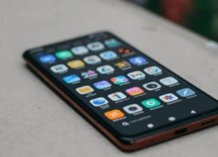 celular xiaomi mostrando tela de aplicativos em cima de uma mesa