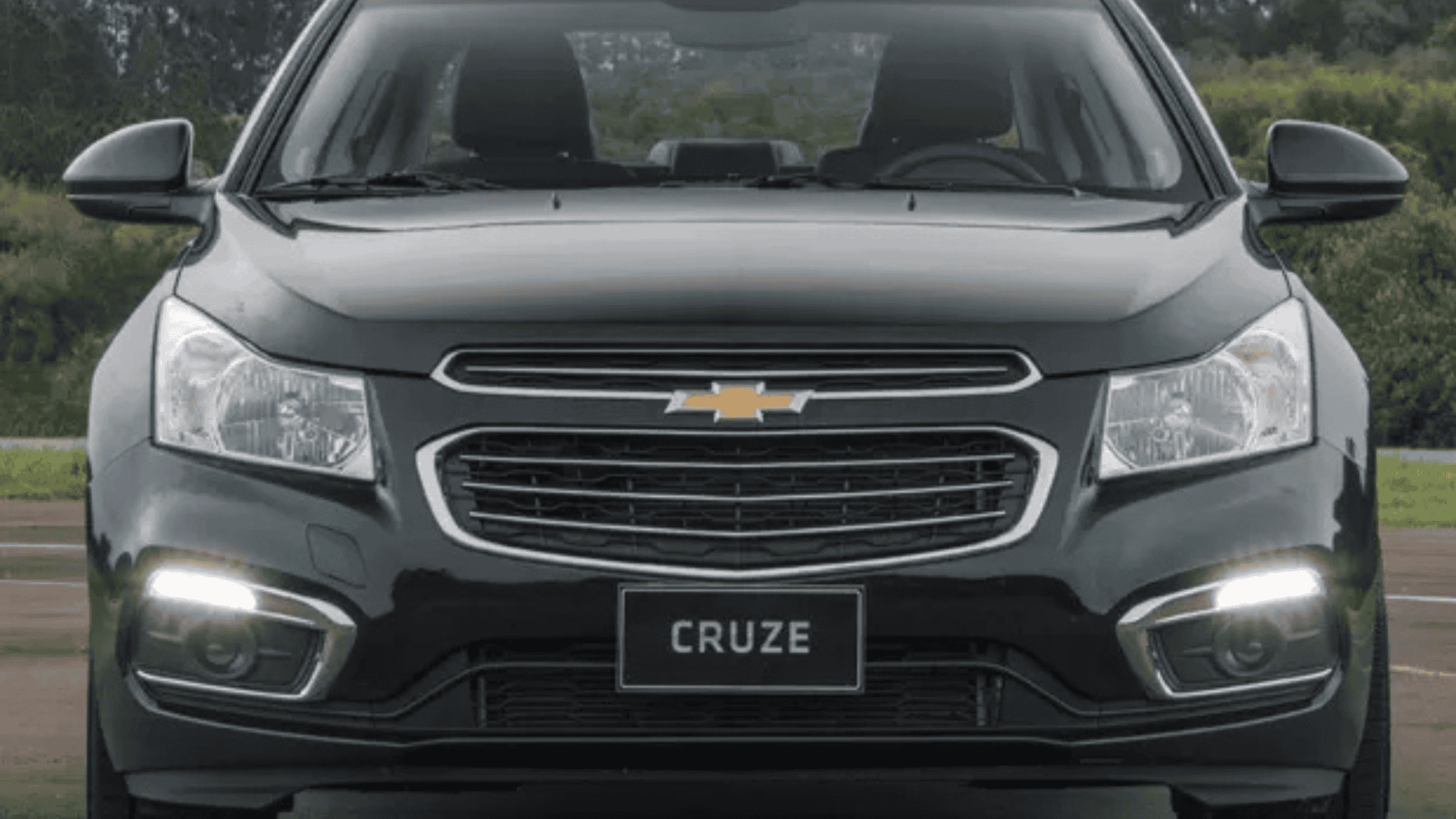 carro sedan preto visto de frente, estacionado numa estrada de terra