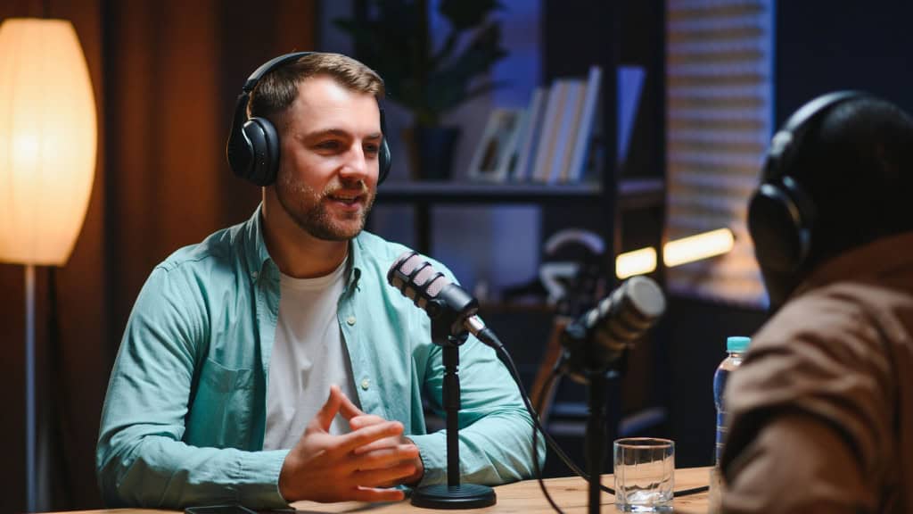 Podcasters desfrutando de conversas felizes com ouvintes on-line em estúdio, cobrindo uma ampla gama de assuntos.