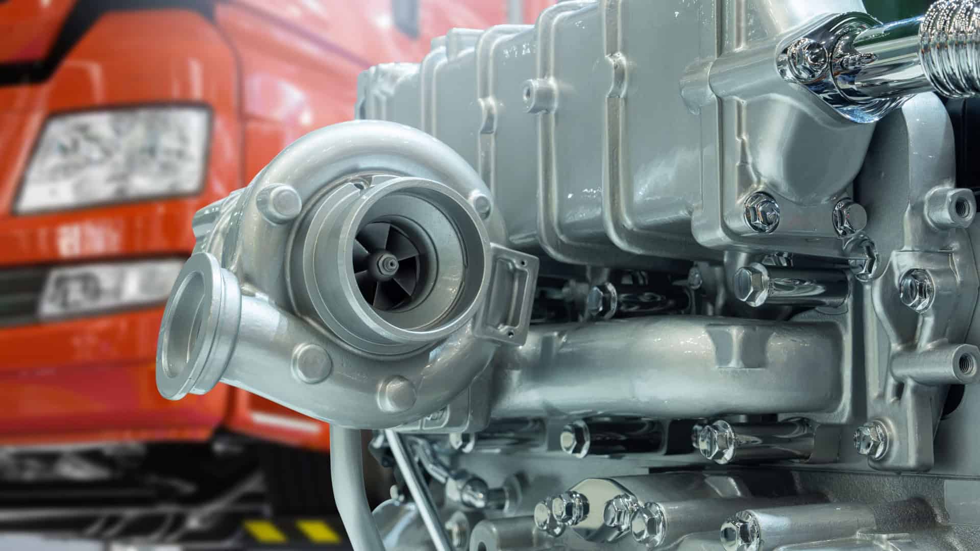 Close de turbocompressor de motor diesel A imagem mostra um motor turbo automotivo, com tubos metálicos conectados a diferentes componentes. Há uma carcaça cilíndrica central, responsável por comprimir o ar antes de enviá-lo ao motor. Os detalhes mecânicos e conexões refletem sua função de otimizar o desempenho do veículo.