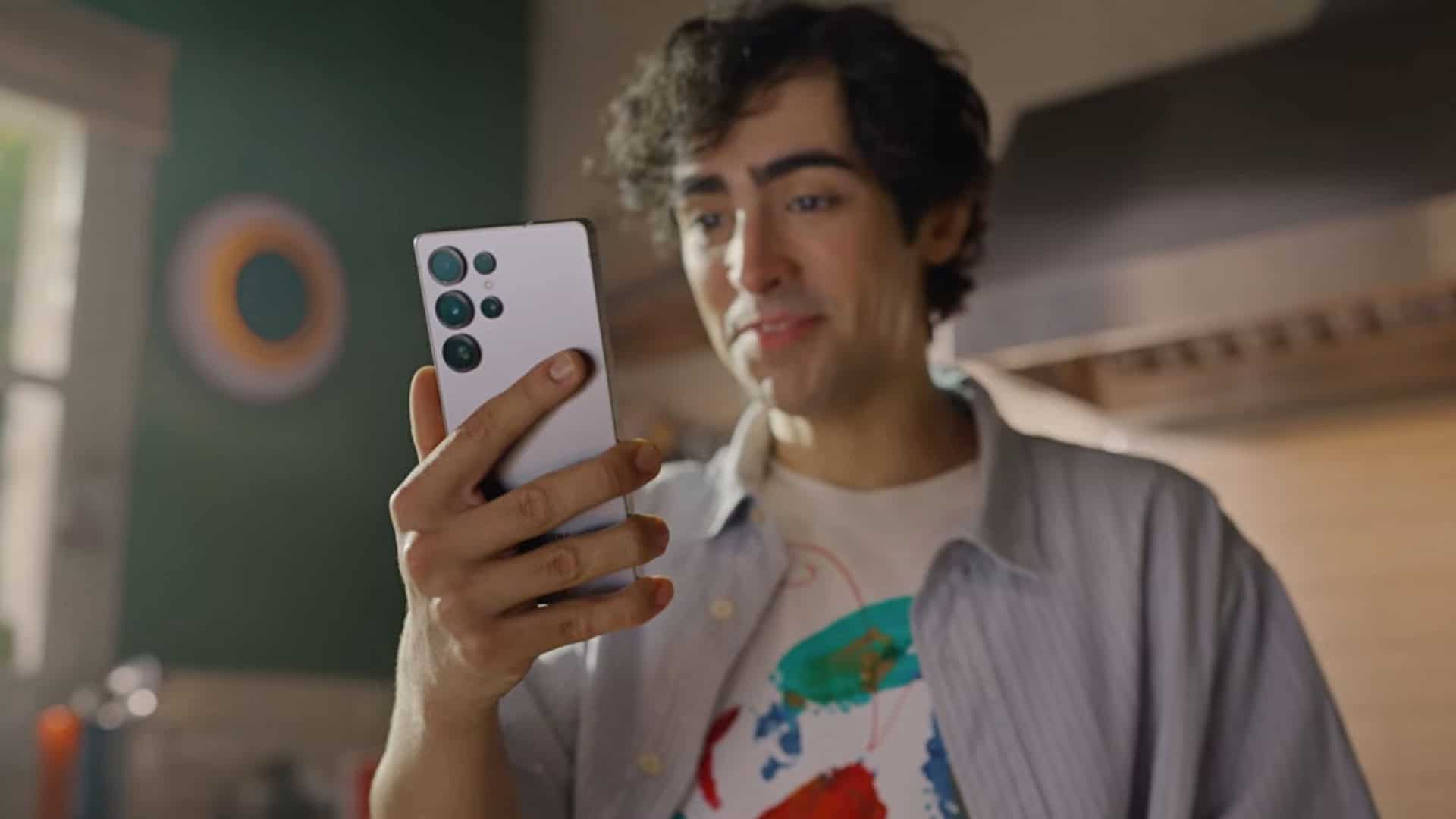 Rapaz segurando Galaxy S25 enquanto conversa com Gemini, IA do Google, numa cozinha