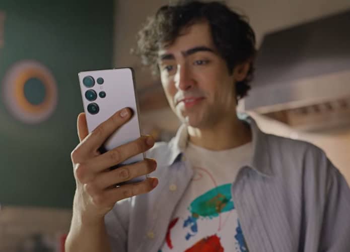Rapaz segurando Galaxy S25 enquanto conversa com Gemini, IA do Google, numa cozinha
