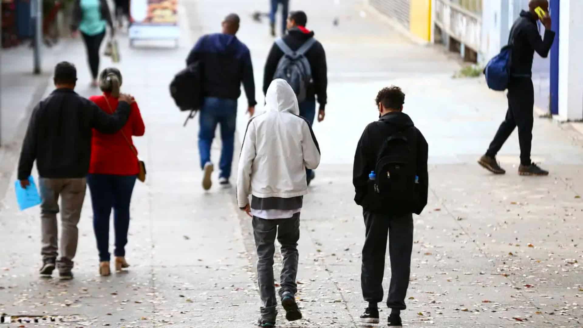 Pessoas andando agasalhadas na rua em dia frio