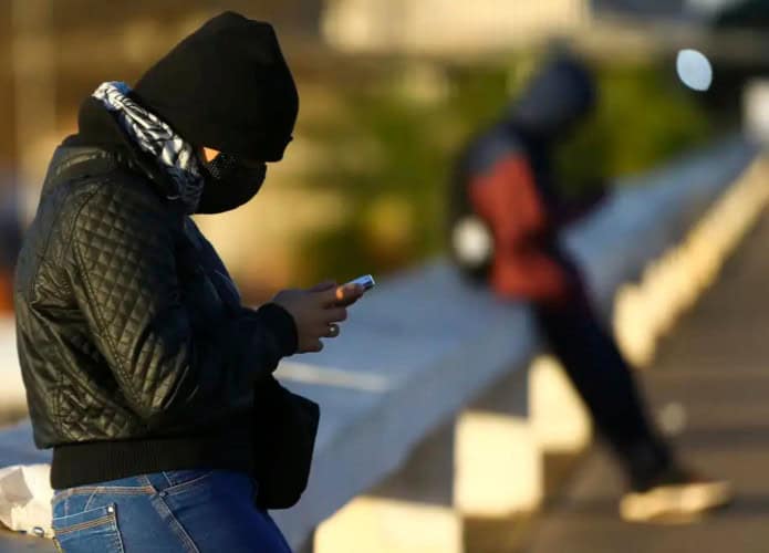 Duas pessoas muito agasalhadas encostadas em mureta durante dia frio