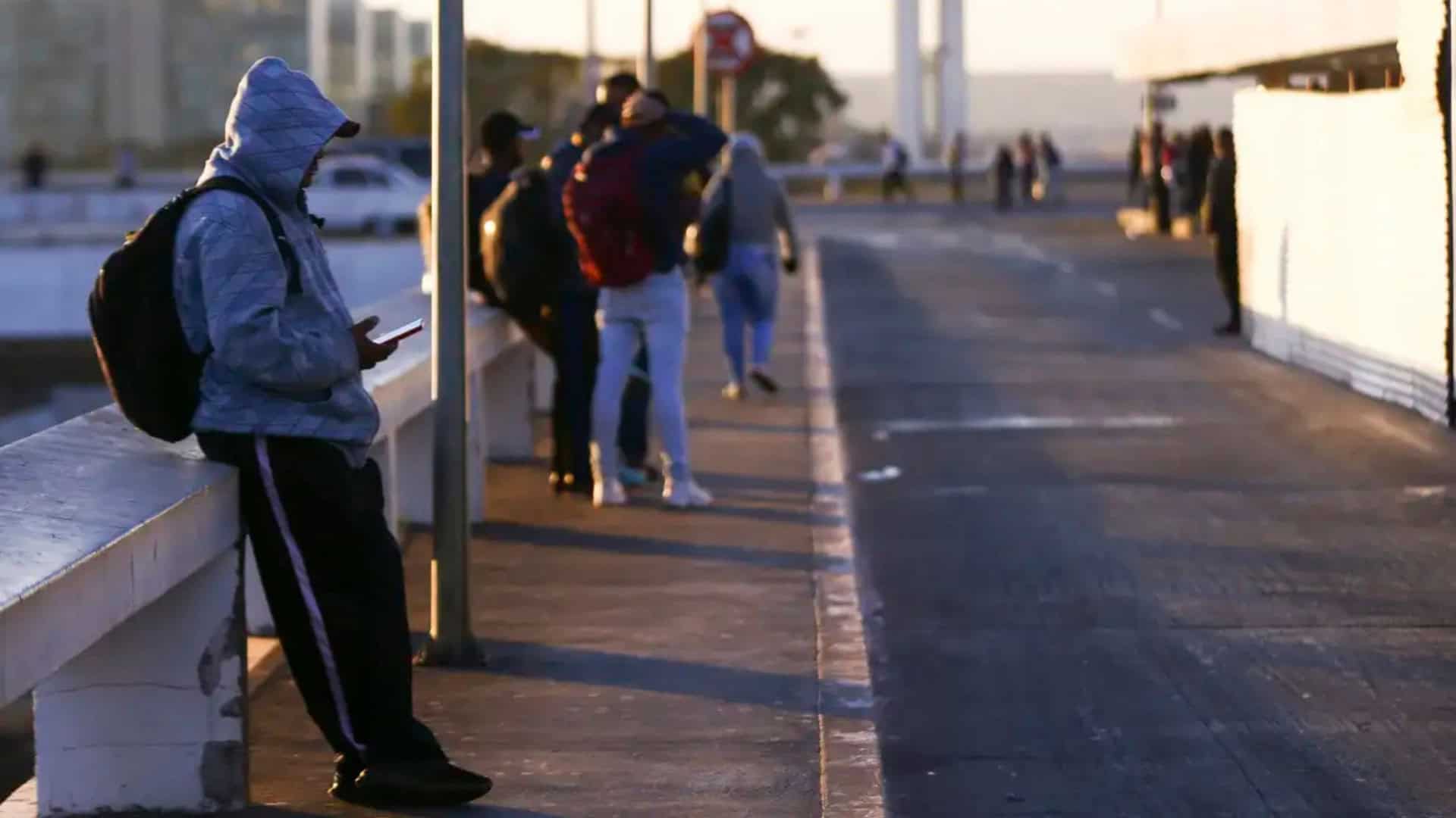 Pessoas agasalhadas encostadas em mureta durante dia frio