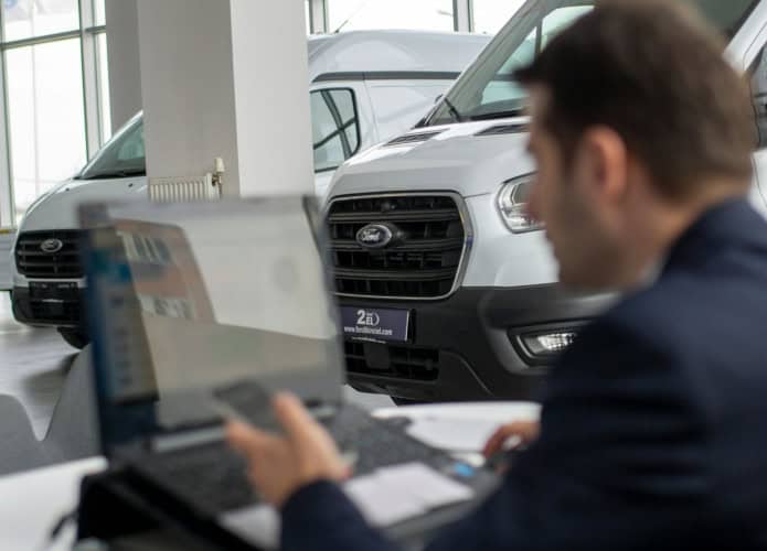 homem olhando o computador próximo a carros