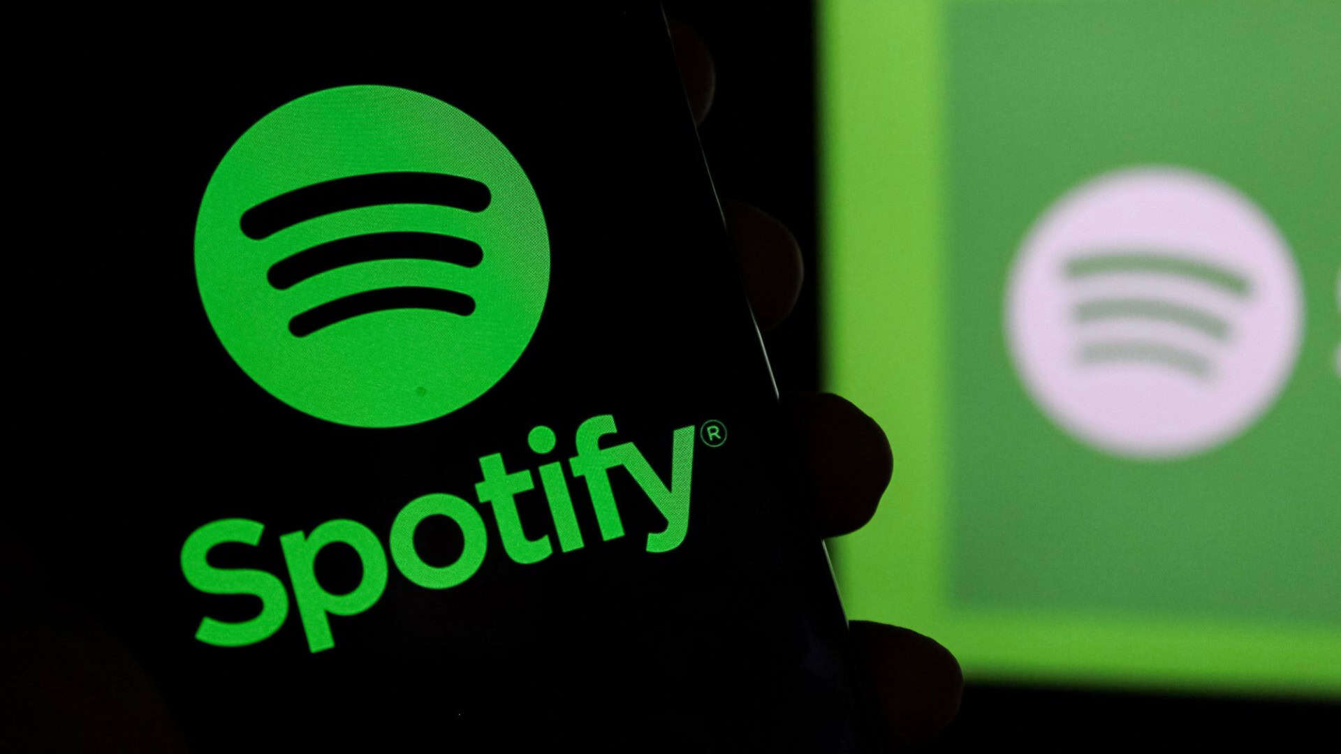 Logo do Spotify em um smartphone e ao fundo