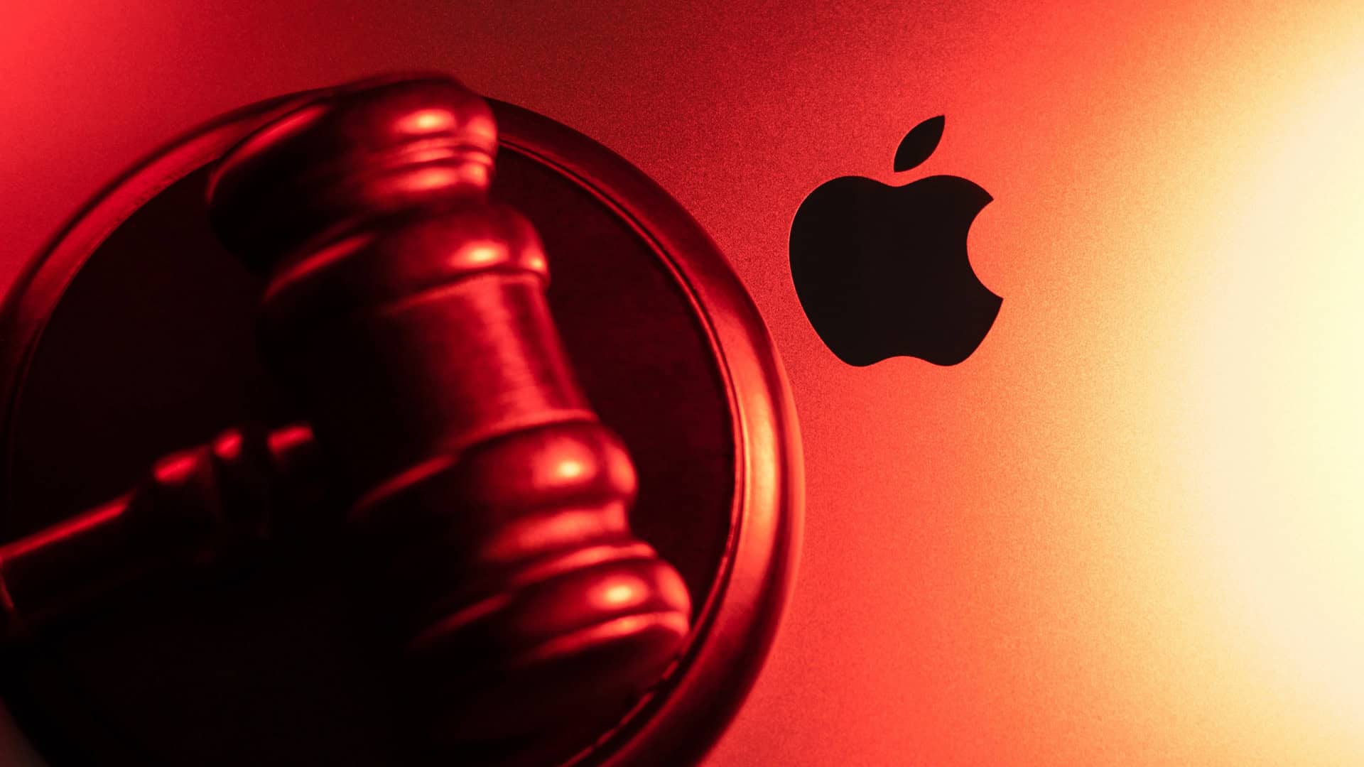 Martelo de juiz em cima de um MacBook; em destaque, o logo da Apple