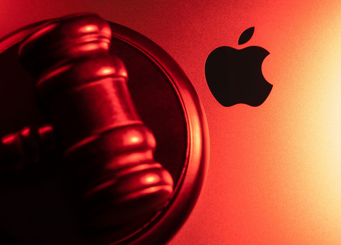 Martelo de juiz em cima de um MacBook, exibindo o logo da Apple ao lado