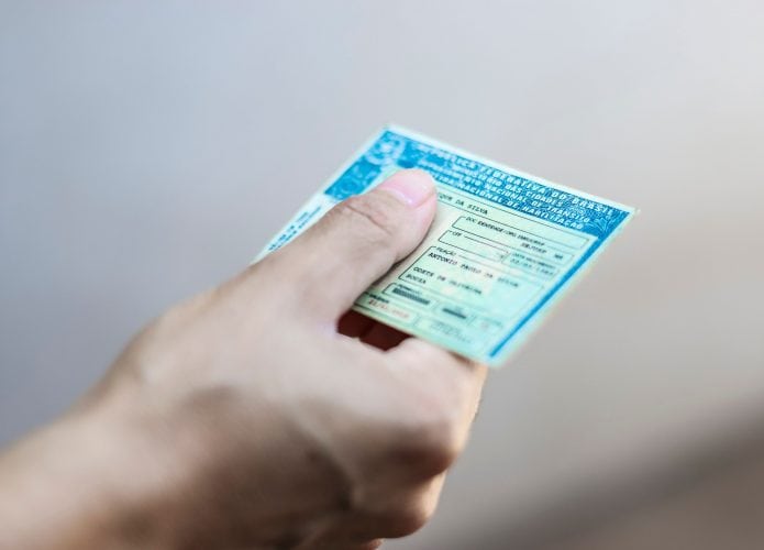 Imagem ilustrativa de mão segurando a CNH (Carteira Nacional de Habilitação)