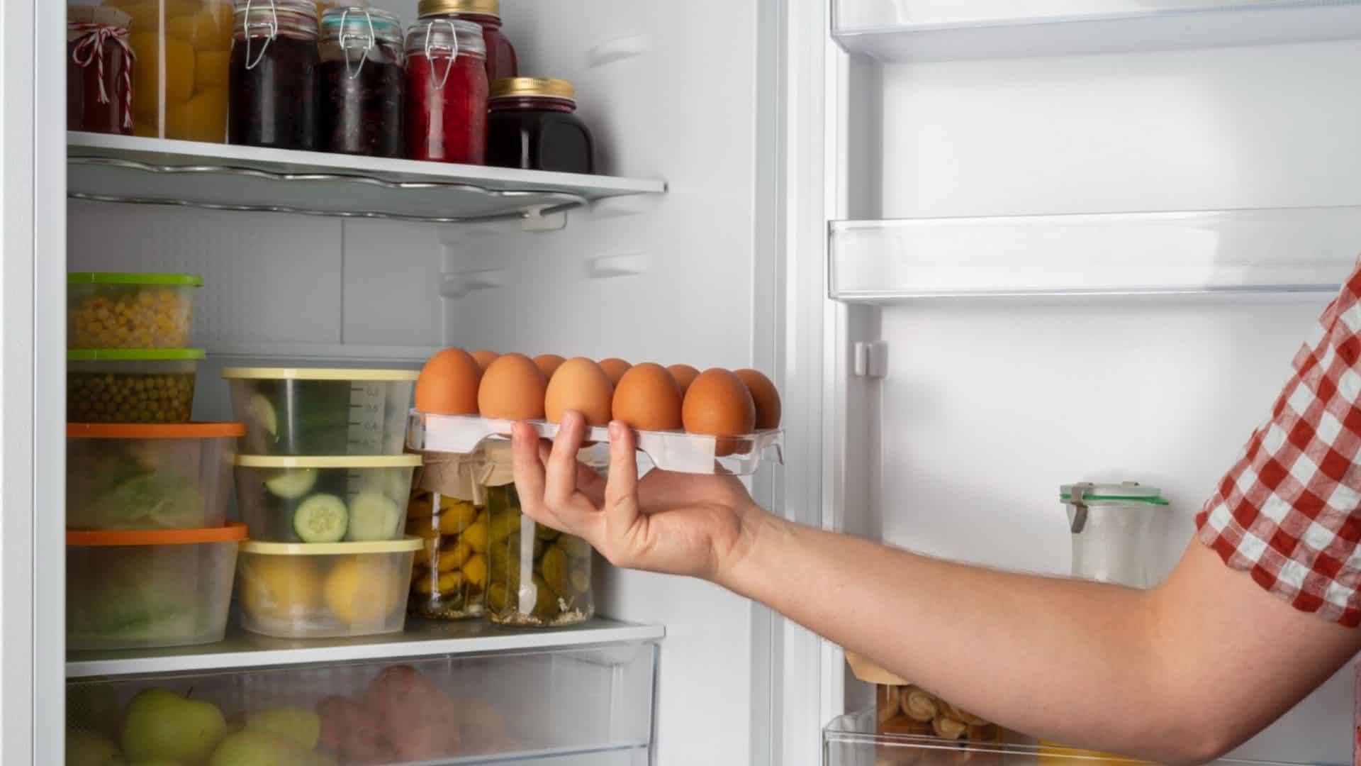 pessoa pegando ovos de uma geladeira com diversos alimentos