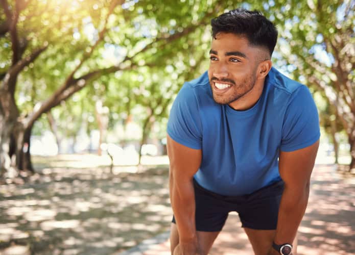 Homem jovem e saudável pratica corrida em parque