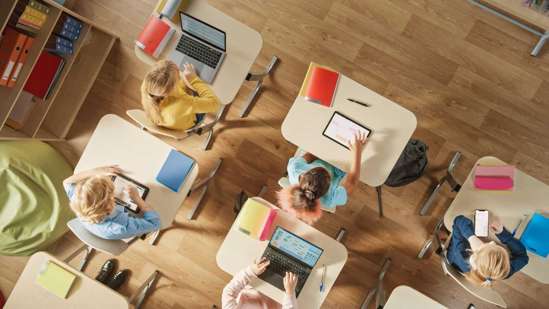 Tomada do alto de crianças sentadas em carteiras escolares