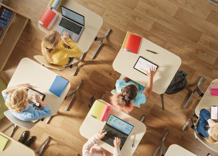 Tomada do alto de crianças sentadas em carteiras escolares